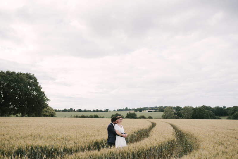 Mariés souriants dans un champ de fleurs, reportage mariage champêtre Grenoble.