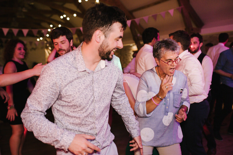 Invités dansant sous les lumières, soirée de mariage festive et conviviale.