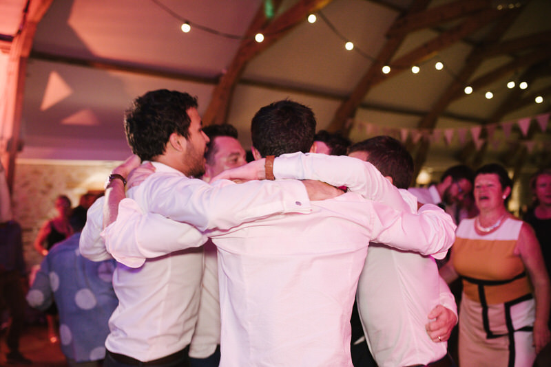 Invités dansant sous les lumières, soirée de mariage festive et conviviale.