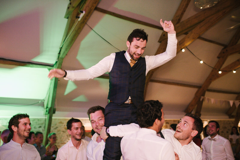 Invités dansant sous les lumières, soirée de mariage festive et conviviale.